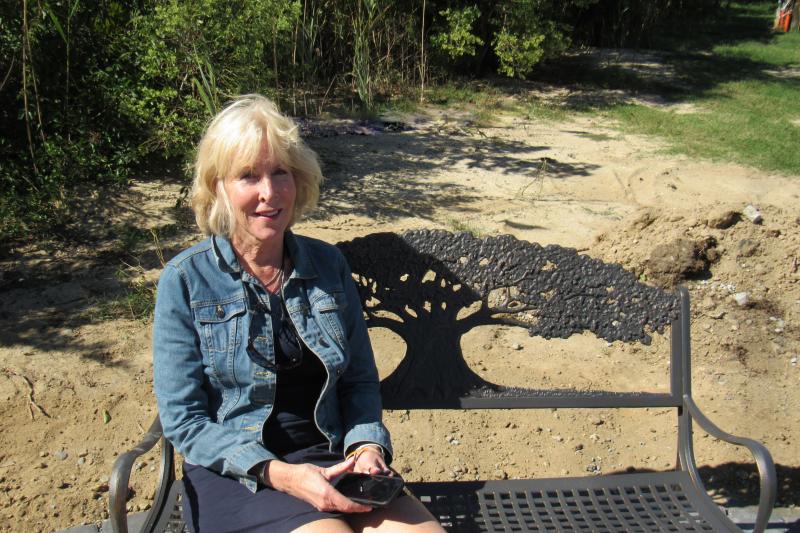 Laura Ashby takes a seat on one of the benches in the small memorial created to honor her son, Dave Ashby. ELLEN DRISCOLL PHOTO